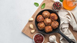 bolinho de carne em uma panela sobre uma tabua de madeira