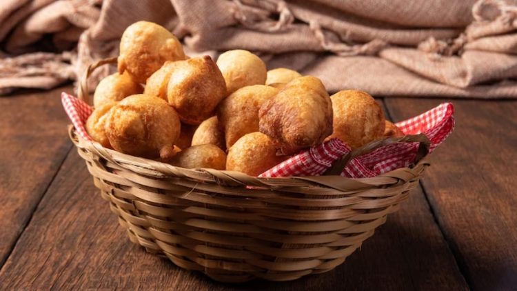 Bolinhos de chuva em cesta marrom e mesa de madeira