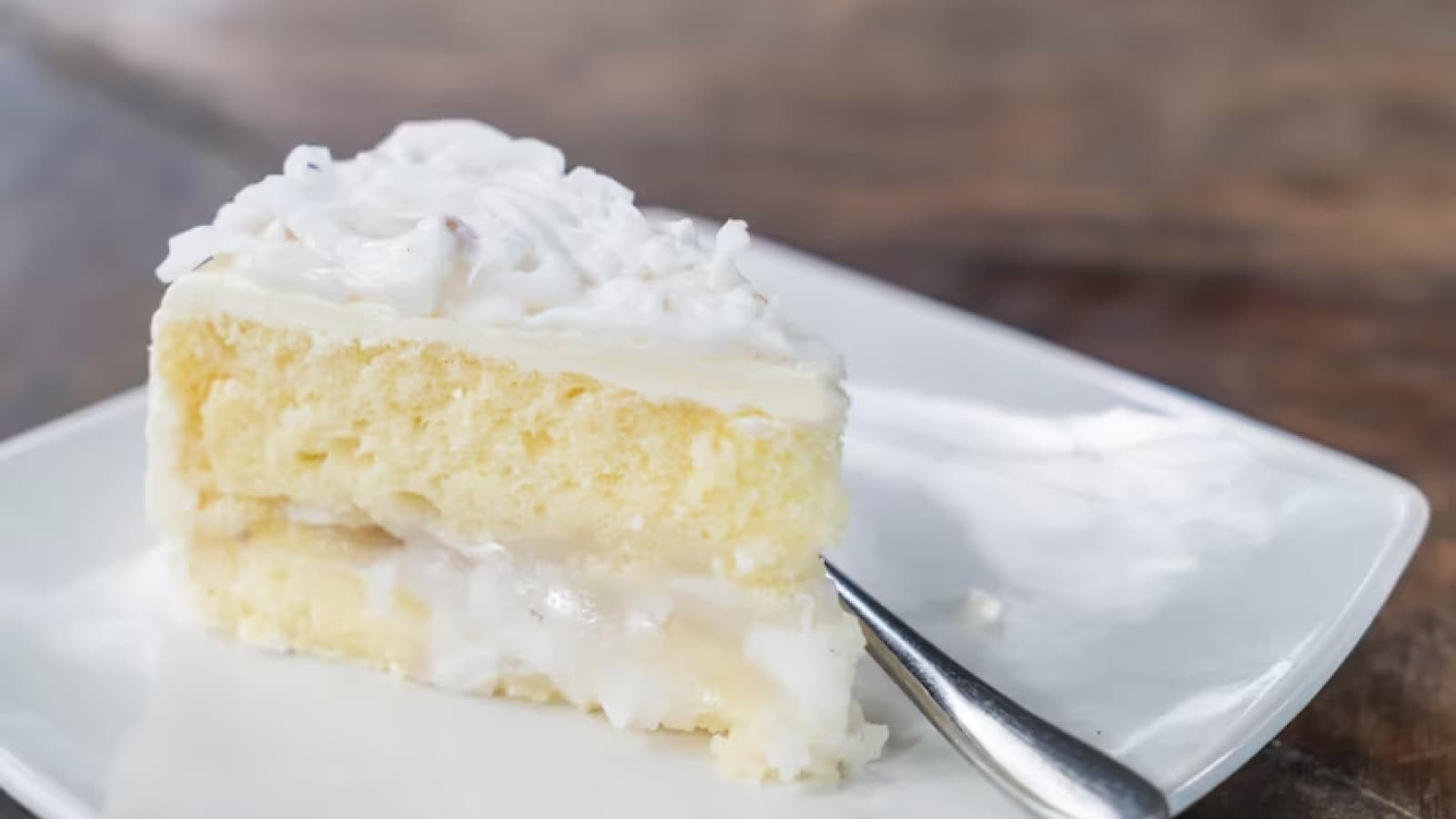 fatia de bolo de leite ninho em prato branco com talher