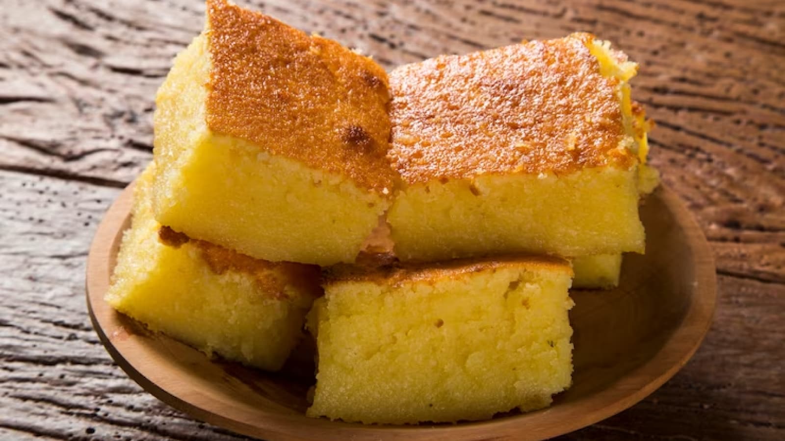 pedaços de bolo de mandioca empilhados em um prato de madeira