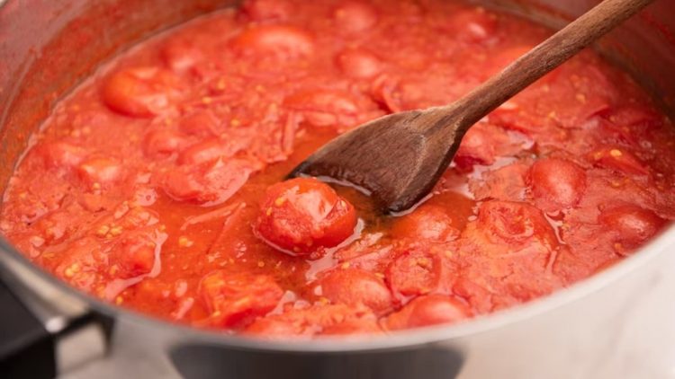 Molho de tomate em uma panela com uma colher de pau